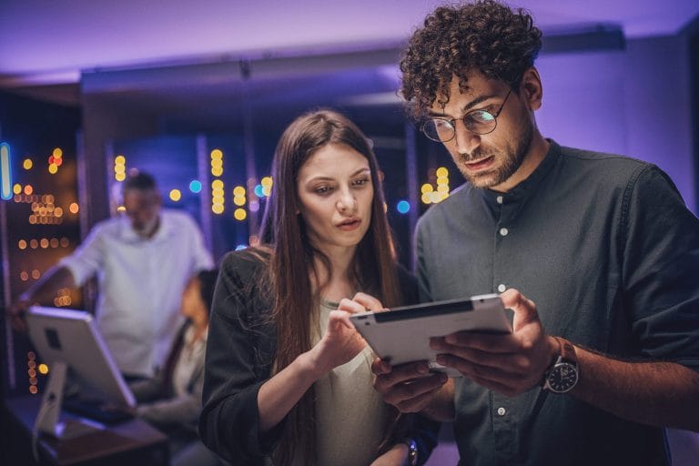 Two coworkers focused on tablet.